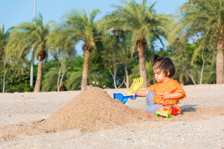 劳动节快乐字体摄影照片_快乐的女儿女孩有趣地挖掘玩沙子玩具