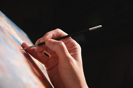 一个女人在画画时手拿着画笔的特写