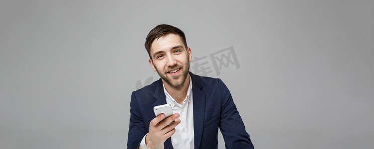 经营理念-肖像英俊快乐英俊的商人穿着西装玩手机，在工作办公室用笔记本电脑微笑。