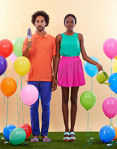 感觉有点格格不入……一对尴尬的非洲夫妇手牵着手，周围环绕着彩色气球。