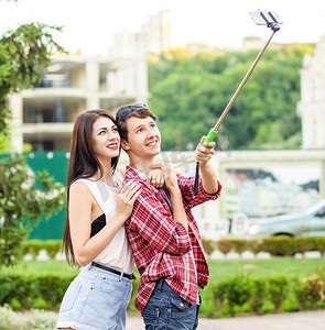快乐的年轻游客夫妇在城市的独脚架上用智能手机自拍。
