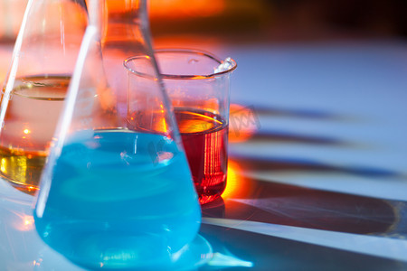 发光的实验室烧瓶，里面装满了五颜六色的化学溶液，桌子上有阴影。