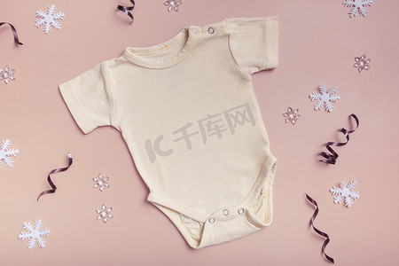 黄色婴儿紧身衣模型，用于粉红色背景上的徽标、文字或设计，并具有冬季装饰顶视图