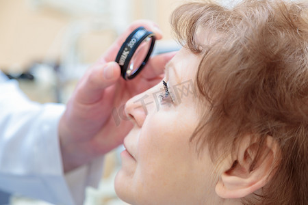 男性眼科医生用双目检眼镜检查成年女性的视力