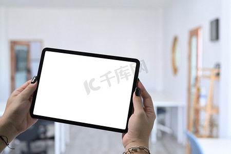 滑雪板样机摄影照片_手持和显示带有模糊咖啡馆背景的数字平板电脑的样机图像。