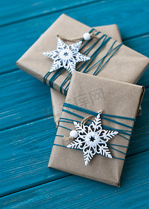 用牛皮纸包裹的三份礼物，上面有两个雪花形状的白色圣诞饰品。