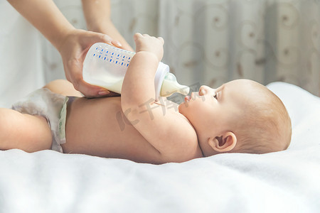 可爱的奶瓶摄影照片_妈妈用奶瓶喂婴儿。