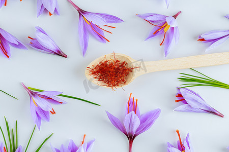 白色紫色白色摄影照片_藏红花柱头在白色背景上的勺子中干燥。
