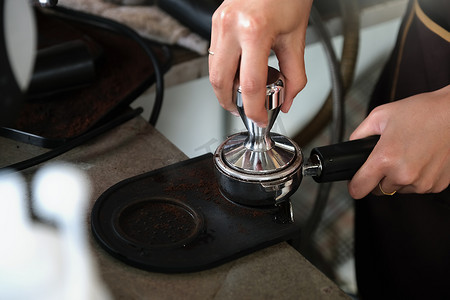 女工在将烘焙好的咖啡豆放入咖啡机之前用捣棒压压