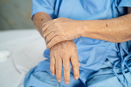 亚洲老年或老年老妇人患者在护理医院病房的床上感到手痛，健康强大的医疗理念。