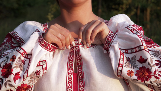 乌克兰妇女用传统装饰品在绣花衬衫上扣上纽扣。
