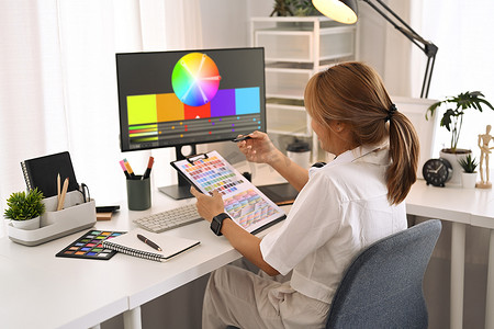 创意女性使用调色板，为现代图形工作室的设计项目选择颜色样本