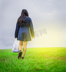 提着购物袋在田野里行走的女人，在田野路上行走的女人