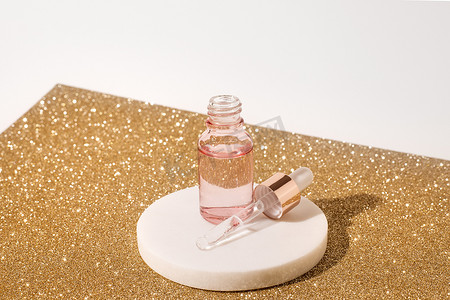 粉红色玻璃瓶化妆品液体透明凝胶在白色背景与金色片材。