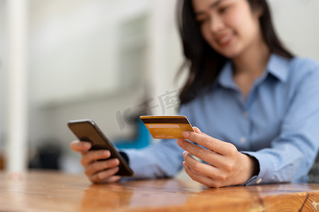 持有信用卡和使用智能手机进行网上购物的年轻女子。
