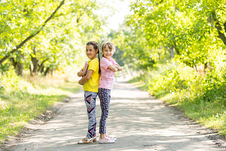 明媚的秋日，两个带着书本的小女学生在城市公园里