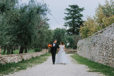幸福天降摄影照片_幸福时尚微笑的夫妇在婚礼当天在意大利托斯卡纳散步。