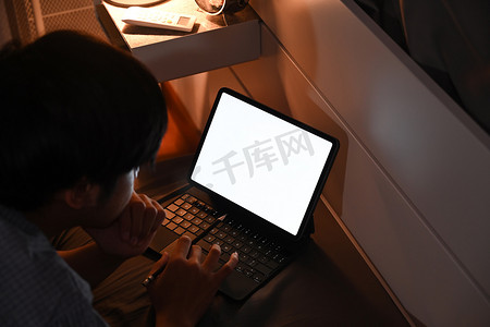 男人晚上在卧室里用电脑桌浏览互联网。
