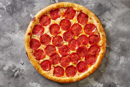 灰色石头背景中带番茄酱和马苏里拉奶酪的辣香肠比萨饼