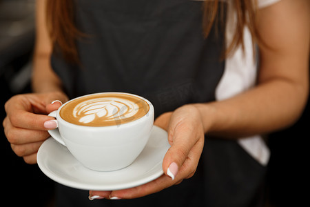 咖啡经营理念 — 站在咖啡店里，女性用拿铁艺术服务咖啡的特写镜头。