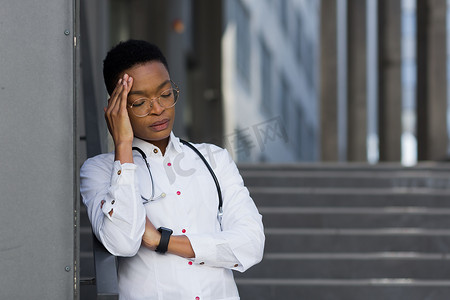 辛苦的妇女摄影照片_在诊所辛苦一天后疲惫的女医生，诊所的一名非裔美国妇女