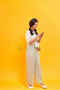 智能工控摄影照片_使用智能手机和提着棕色篮子的亚洲美女。