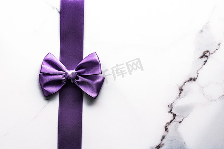 豪华大理石背景上的紫色丝带和蝴蝶结，假日平面背景