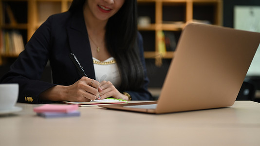 女性企业家使用笔记本电脑并在笔记本上编写商业计划的剪影