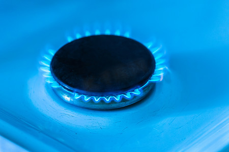 燃烧器摄影照片_燃气灶上有蓝色火焰的燃气燃烧器，特写