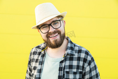 正面的年轻嬉皮士男子在黄色墙壁商店户外背景上微笑的肖像 — 戴着帽子和眼镜站在户外的英俊时髦的留着胡子的男人 — 时尚和时髦的年轻人概念
