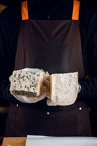 蓝色布纹摄影照片_蓝纹奶酪和豪达，手中有意大利香草。