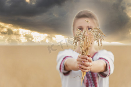 夕阳的天空背景下，手里拿着小麦的女孩