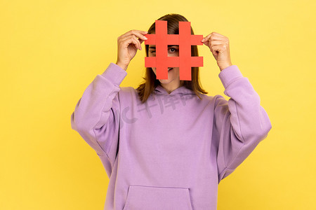 人气标签摄影照片_女性用社交媒体标签符号遮住脸，建议关注流行内容。