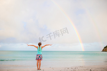 快乐的小女孩背景美丽的彩虹在海上