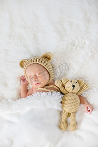 抱着小熊摄影照片_刚出生的婴儿抱着泰迪熊睡觉。