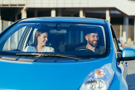 男驾驶教练和女驾驶学校学生一起坐在车里微笑着学习驾驶汽车