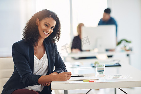快乐的企业女商人在办公桌前工作，在办公室工作时进行管理并记笔记。