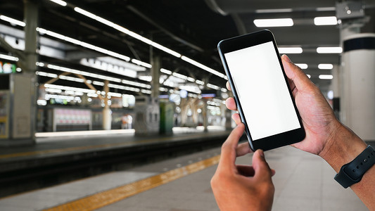 男子手拿着智能手机有火车站背景。