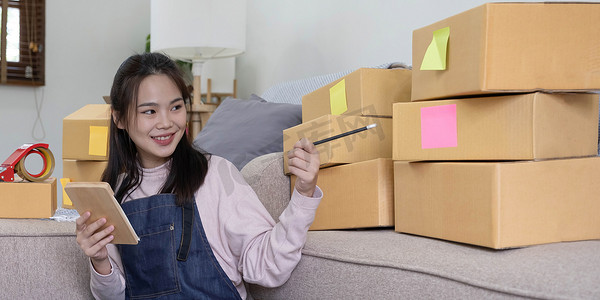 创业小企业主女企业家的肖像在收据箱上工作并检查在线订单以准备包装箱子、向客户销售、在线中小企业商业创意。