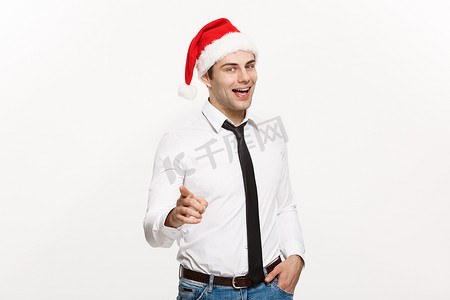 圣诞节概念-英俊的商人戴圣诞老人帽子，手指指向白色孤立的背景。