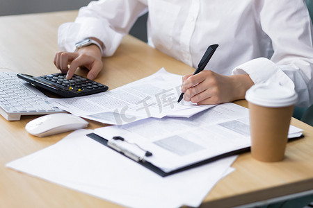 一位女商人手写文书工作的特写照片，一位会计师用计算器计算和总结财政年度的结果，一位亚洲女性在办公室工作