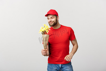 送花的男人摄影照片_送花概念：快乐送花人的肖像，手捧美丽的花束，在白色背景下用手指指着相机