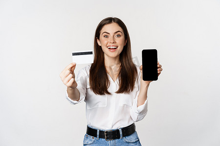 女性模特肖像显示信用卡与智能手机屏幕，推荐应用程序，站在白色背景