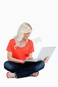 年轻的金发女郎盘腿坐在她的 l 上，她的笔记本电脑