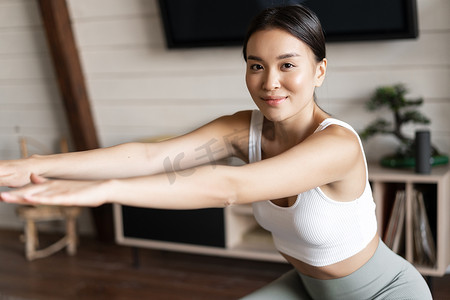 可爱的亚洲健身女孩在家锻炼，腿上拉着弹力绳蹲下，锻炼身体健康