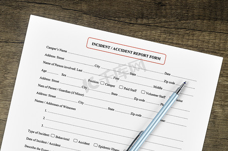 事故报告表与木制背景上的笔。