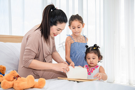 母亲读书摄影照片_亚洲母亲教混血女孩女儿在家里读书。