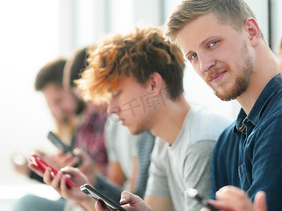 一群拿着智能手机的年轻人坐在一排