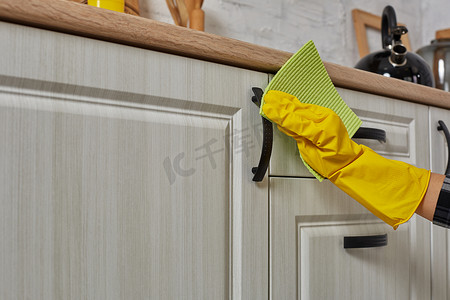 手戴绿色抹布的手套正在清洁厨柜 — 家务和家政概念