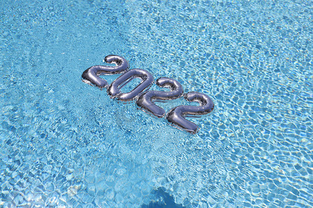 蓝色洁净泳池水中漂浮的银箔数字，节日装饰